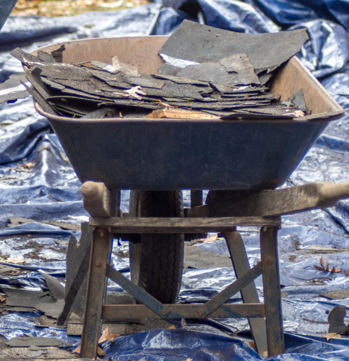 Construction debris and old shingles are removed in a wheel barrel by Gator-Done junk removal